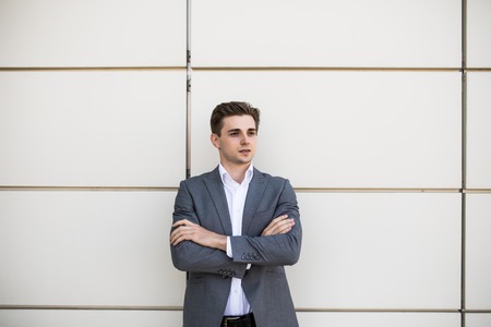portrait of a businessman standing with his arms folded with office buildings in backgroundの写真素材