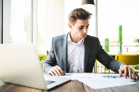 business, people, fail, paperwork and technology concept - businessman with laptop computer and papers working in officeの写真素材