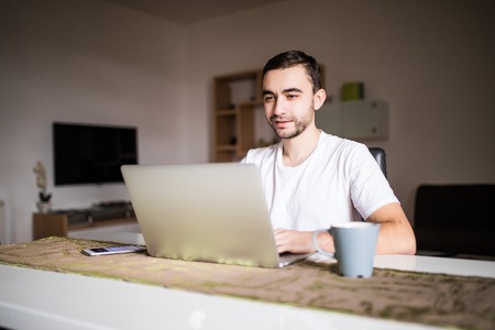 Portrait Of Young Man Using Laptop While Having Breakfastの写真素材