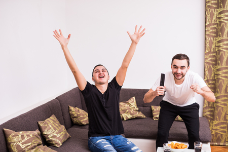 buddies watching football match on tv at homeの写真素材