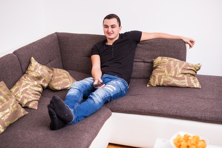 Young handsome man watching TV on a sofaの写真素材