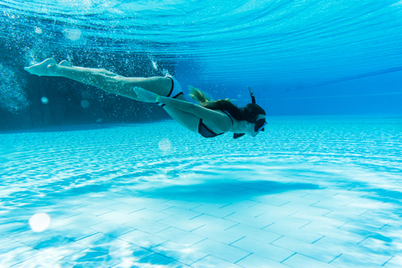 Woman wearing snorkeling mask swimming under waterの写真素材