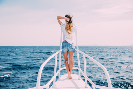 Woman standing on yacht nose on sea backgroundの写真素材