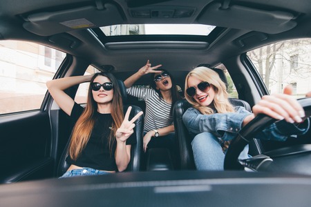 Group of friends having fun on the car. Singing and laughing in the cityの写真素材