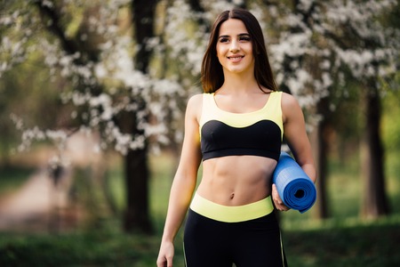 Beautiful woman with a yoga mat outdoors.の写真素材