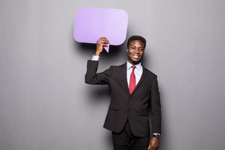 Handsome Afro American man in classic suit is holding a speech bubble and thinking