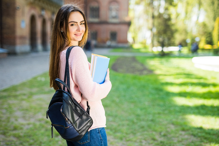 American university student smiling with coffee and book bag on campus with print spaceの写真素材