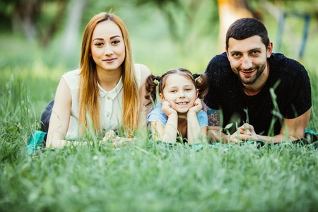 Happy family of three lying on grass. happy family relations and carefree leisure timeの写真素材