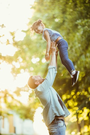Father and daughter are playing and hugging outdoors in summer park on sunset.の写真素材