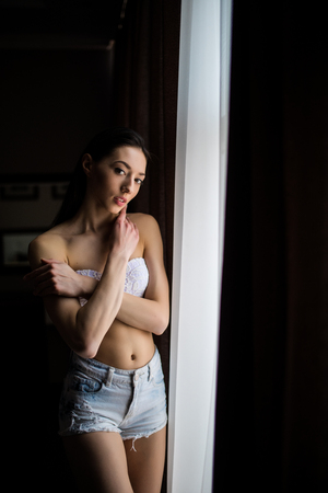 portrait of young beautiful woman posing behind white curtainsの写真素材