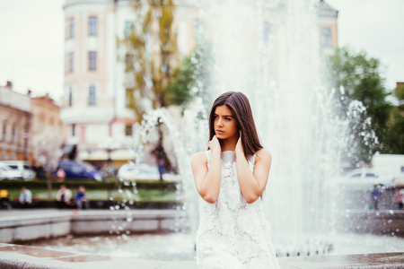 Young beautiful stylish girl walking and posing in city near fountains.の写真素材