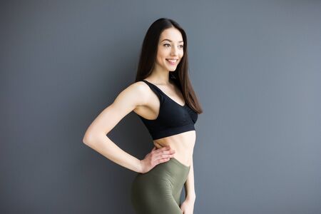 studio photo of posing sexy woman with nice fitness body isolated over gray background