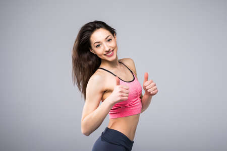 Beautiful fitness model showing thumb up on white backgroundの写真素材