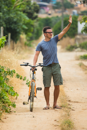Handsome man in sun glasses is smiling while cycling in the parkの写真素材