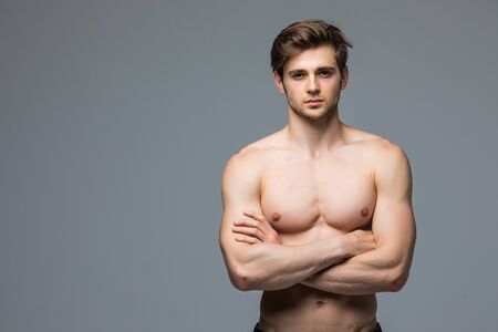 Muscular athlete bodybuilder man with a naked torso on a gray