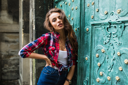 cute smiling woman on a background of green vintage door wearing casual clothes in summer cityの写真素材