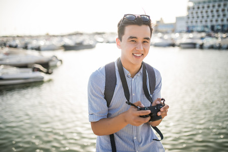 Young asian man look at taked photo in travel near marina in old cityの写真素材