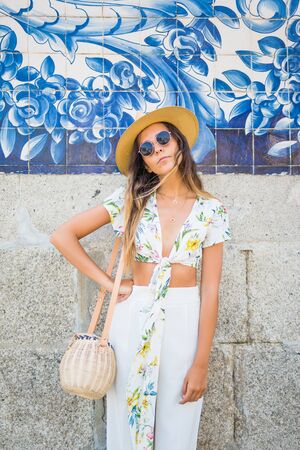 woman near city wall wearing sunglasses and white t-shirt at hot summer day in the cityの写真素材