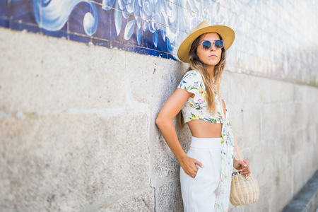 woman near city wall wearing sunglasses and white t-shirt at hot summer day in the cityの写真素材
