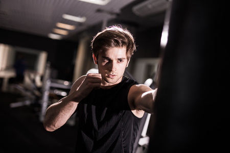Portrait of boxer trying to kicking punching bag in gym while trainingの写真素材
