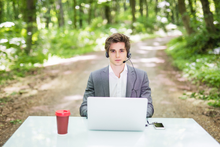 handsome Businessman with headset sitting at the office desk with laptop computer and cup of coffee...