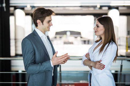 Handsome businessman discuss with businesswoman at the beginning of a meeting in front of panoramic windowの写真素材