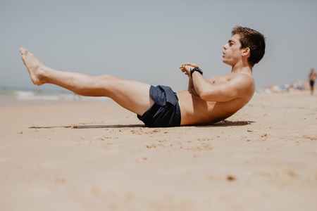 Side view portrait of a young man exercising on the beach