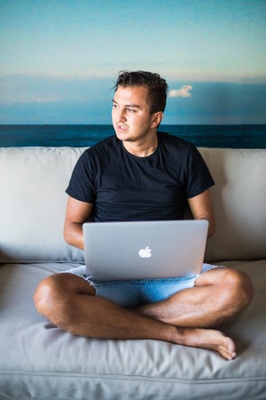 Happy young man watching and working on computer laptop at homeの写真素材
