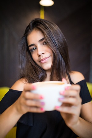Charming girl with having great time, drinking cup of cappuccino, latte, coffee in morningの写真素材
