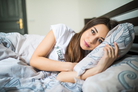 portrait of a calm young pretty woman sleeping and hugging pillow in bedの写真素材
