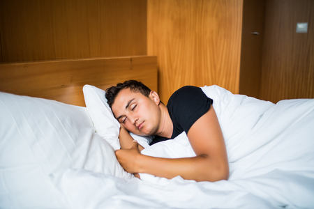 Man comfortably sleeping in his bed at nightの写真素材