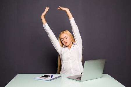 businesswoman looking at work on laptop computer with satisfaction and stretching arms in the air.の写真素材