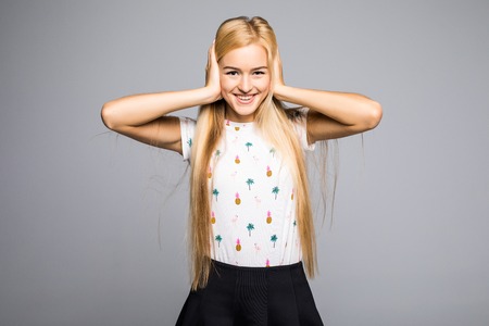 Pretty woman covering her ears with fingers and showing teeth with smileの写真素材