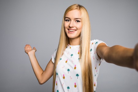 Happy cute woman making selfie over grayの写真素材