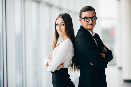 A business man and woman are standing with back to backの写真素材
