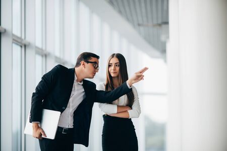 Beautiful businesswoman listening to her colleague at the meeting about changes panoramic office. Business man pointed with hands and explain changesの写真素材
