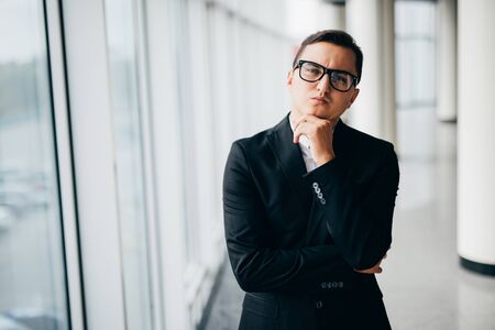 Smiling businessman standing by the window in officeの写真素材