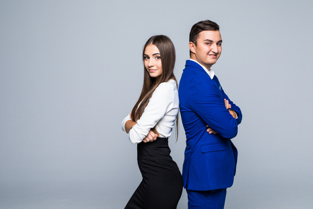 Two professionals in business and finance in gray jackets and jeans standing back-to-back on gray backdropの写真素材