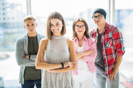 Successful team leader with a warm friendly smile standing with folded arms in front of the friends people comprising her teamの写真素材