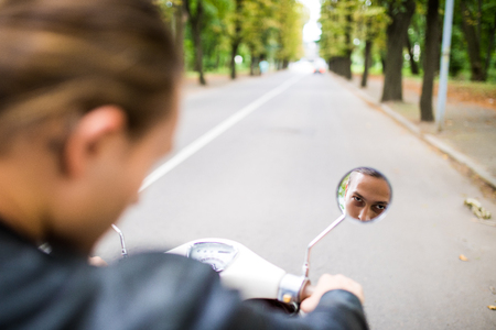 Reflection of a young handsome man in the mirror of the scootersの写真素材