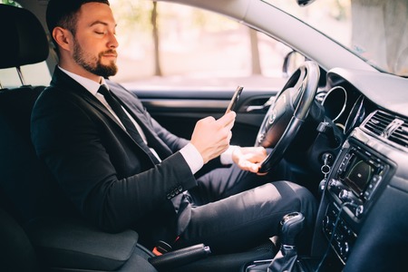 Portrait of handsome business man use phone in car