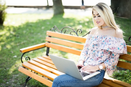 Young woman working on laptop in the parkの写真素材