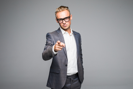 young business man pointing and looking at the camera. on a gray backgroundの写真素材