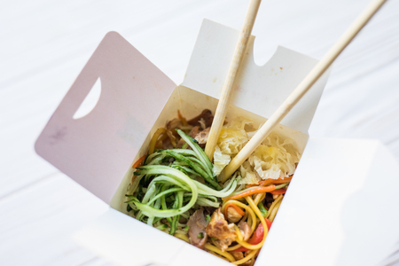 Food. Noodles in a white box on a wooden background close up shotの写真素材