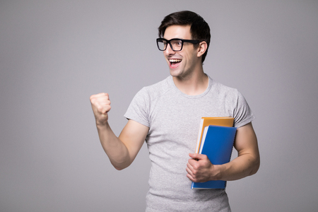 Happy student with backbag holding notebook, guy wearing gray t-shirt and jeans, isolated on white backgroundの写真素材