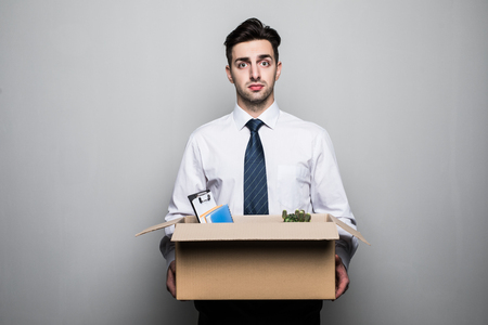 Getting fired. Handsome businessman in suit in office with the box with his stuffの写真素材