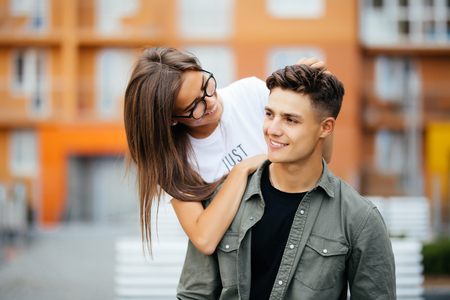 Beautiful young couple in sun glasses looking at each other and smiling while standing outdoors.の写真素材