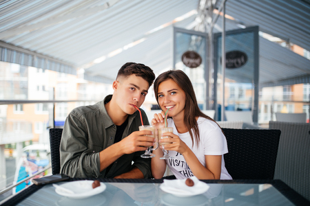 Happy couple is drinking coffee and smiling while sitting at the cafeの写真素材