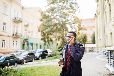 African american man checking his phone and holding a coffeeの写真素材