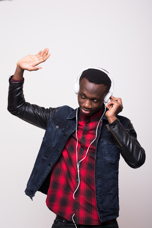 excited african american man listening music in headphones and dancing isolated on whiteの写真素材